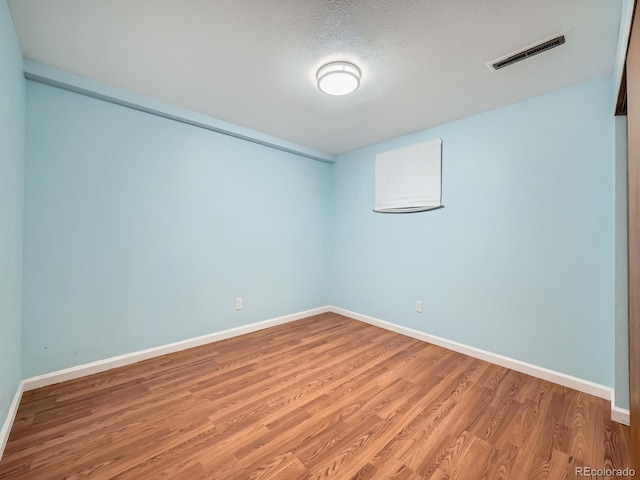 empty room with baseboards, a textured ceiling, visible vents, and wood finished floors