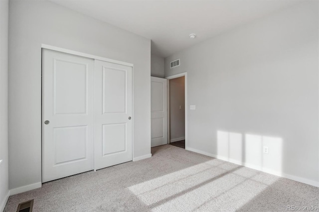 unfurnished bedroom featuring light carpet and a closet