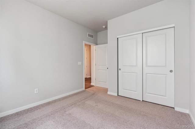 unfurnished bedroom featuring light colored carpet and a closet