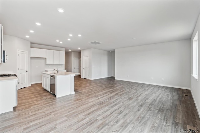 kitchen with light wood-type flooring, a kitchen island with sink, sink, dishwasher, and white cabinetry