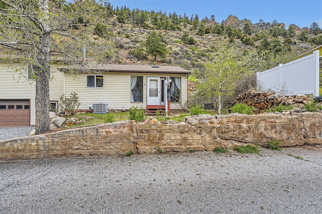 view of front of house featuring fence, central AC, and a garage