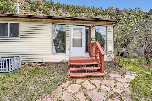 doorway to property featuring central AC unit and fence