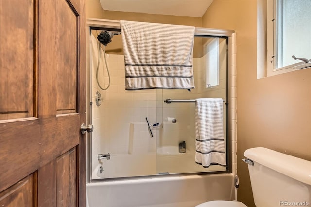 full bathroom with toilet and shower / bath combination with glass door