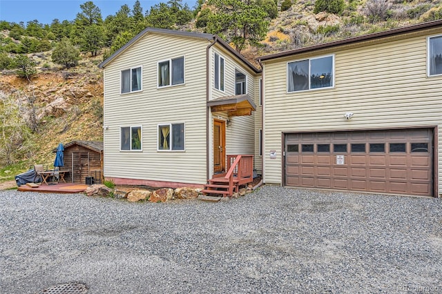 traditional-style house with driveway, an attached garage, and a wooden deck