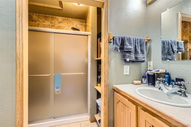 bathroom featuring a stall shower, a textured wall, and vanity