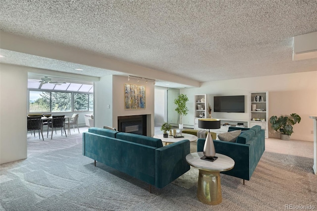 living room featuring light carpet, a glass covered fireplace, a textured ceiling, and rail lighting
