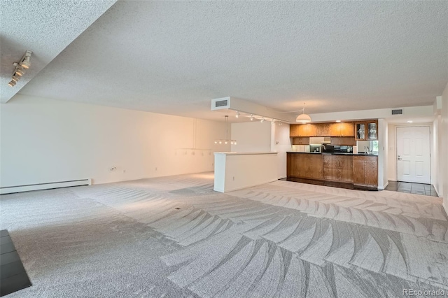 unfurnished living room featuring light carpet, visible vents, a textured ceiling, and rail lighting