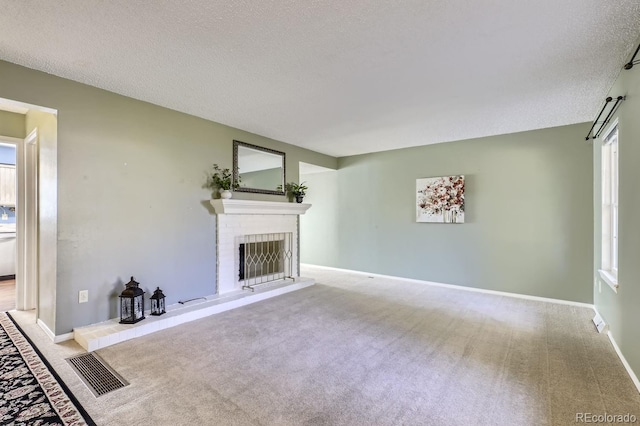 unfurnished living room featuring light colored carpet, a textured ceiling, and a brick fireplace