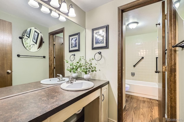 full bathroom with vanity, hardwood / wood-style flooring, toilet, and tiled shower / bath