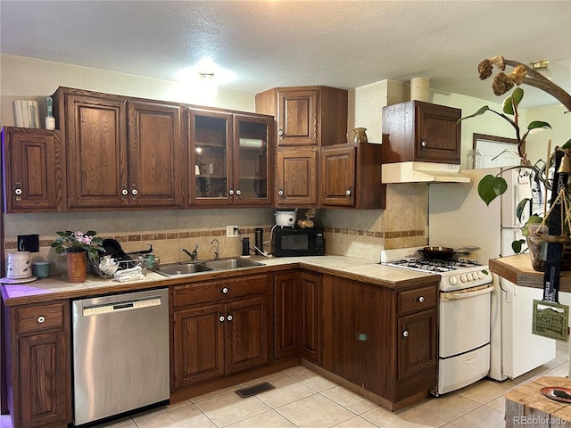 kitchen featuring decorative backsplash, stainless steel dishwasher, dark brown cabinetry, sink, and white gas range oven