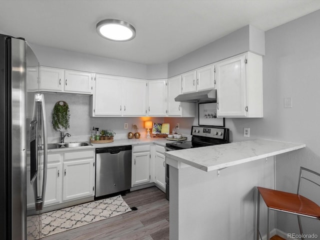 1714 W 102nd Ave, Thornton, CO 80260 - kitchen with appliances with stainless steel finishes, under cabinet range hood, light wood finished floors, a peninsula, and white cabinets