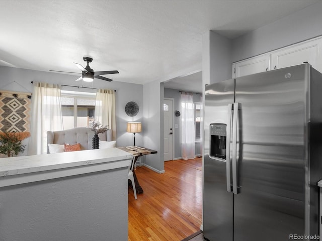 1714 W 102nd Ave, Thornton, CO 80260 - kitchen featuring stainless steel fridge, ceiling fan, light wood finished floors, white cabinetry, and light countertops