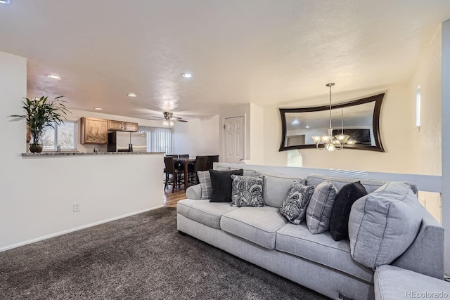 carpeted living room featuring ceiling fan with notable chandelier