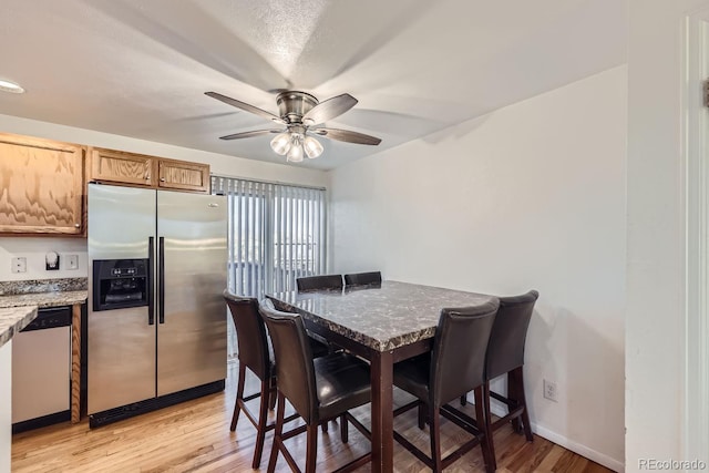 dining area featuring ceiling fan, light hardwood / wood-style flooring, and a textured ceiling