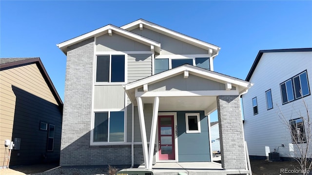 view of front of property featuring covered porch, cooling unit, and brick siding