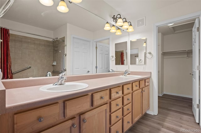 8258 S Sicily Ct, Aurora, CO 80016 - bathroom featuring a tile shower, double vanity, wood finished floors, a spacious closet, and baseboards