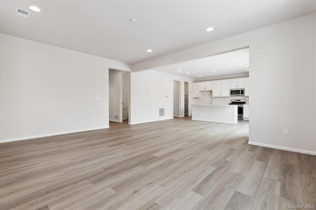 unfurnished living room featuring recessed lighting, visible vents, light wood-style flooring, and baseboards