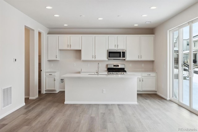 kitchen with visible vents, light wood finished floors, a sink, white cabinets, and appliances with stainless steel finishes