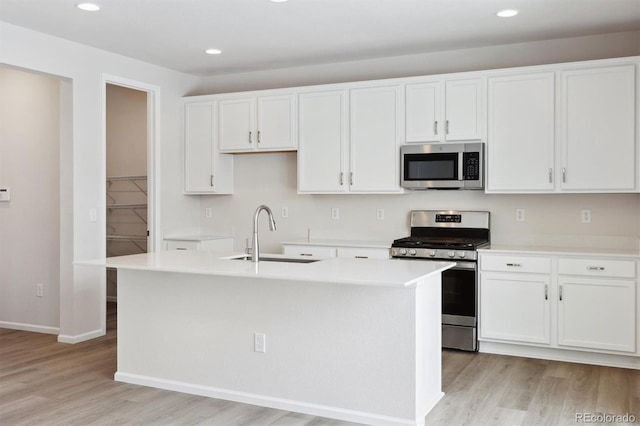 kitchen with white cabinetry, stainless steel appliances, light wood-type flooring, and a sink