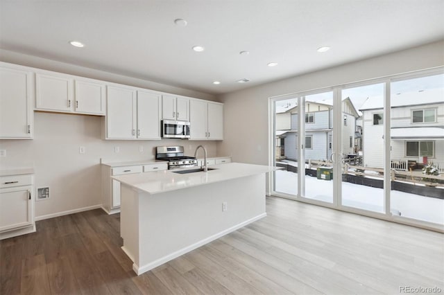 kitchen with wood finished floors, a sink, stainless steel appliances, light countertops, and white cabinets