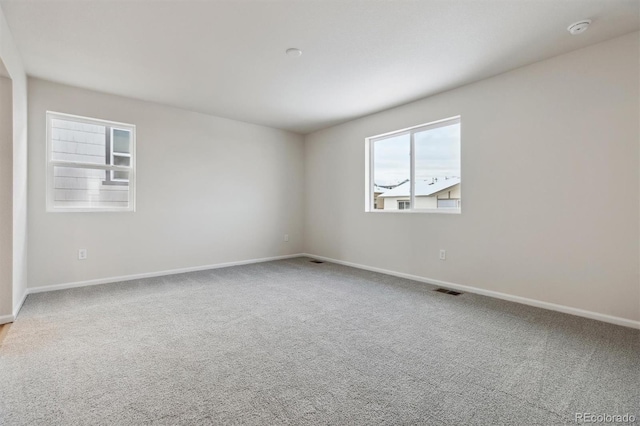 spare room featuring visible vents, carpet floors, and baseboards