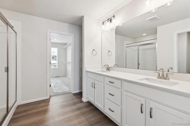 full bathroom featuring a stall shower, wood finished floors, visible vents, and a sink