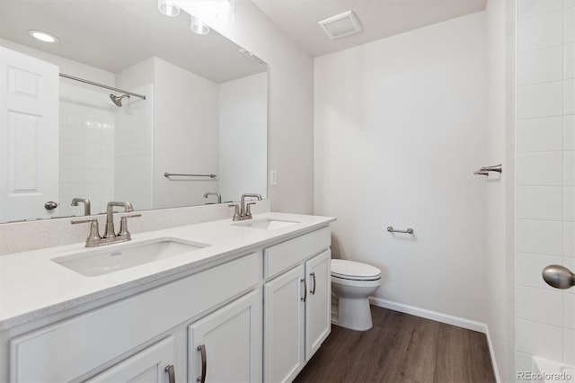 bathroom featuring double vanity, wood finished floors, toilet, and a sink