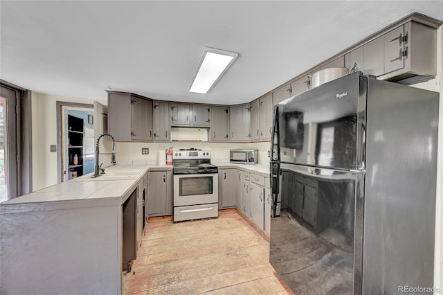 200 Rd P37, Bailey, CO 80421 - kitchen with stainless steel appliances, a peninsula, tile counters, and light wood-style flooring