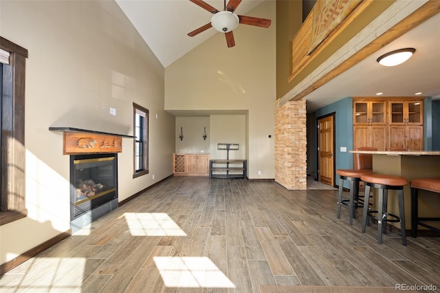127 Silver Sage Rd, Granby, CO 80446 - living room with baseboards, a glass covered fireplace, a ceiling fan, wood finished floors, and high vaulted ceiling
