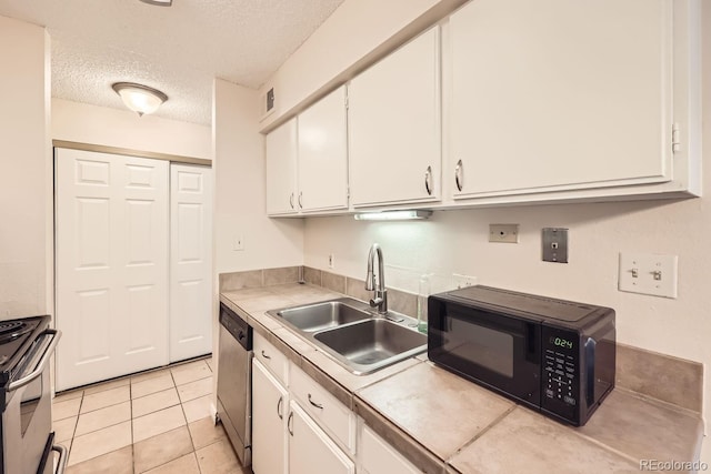 kitchen with white cabinets, sink, light tile patterned floors, a textured ceiling, and appliances with stainless steel finishes