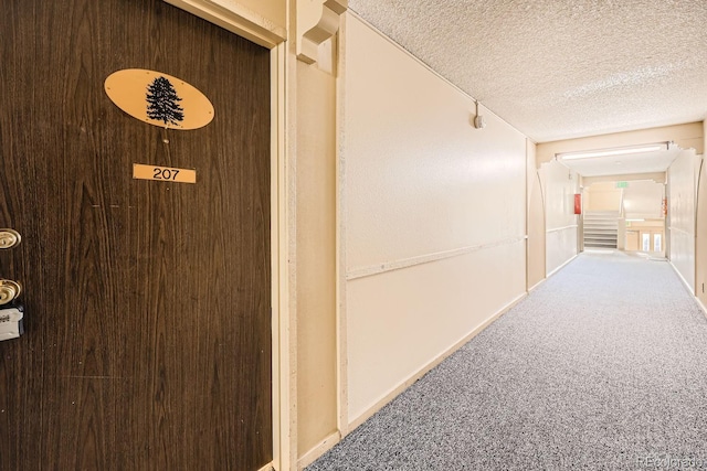 corridor with carpet flooring and a textured ceiling