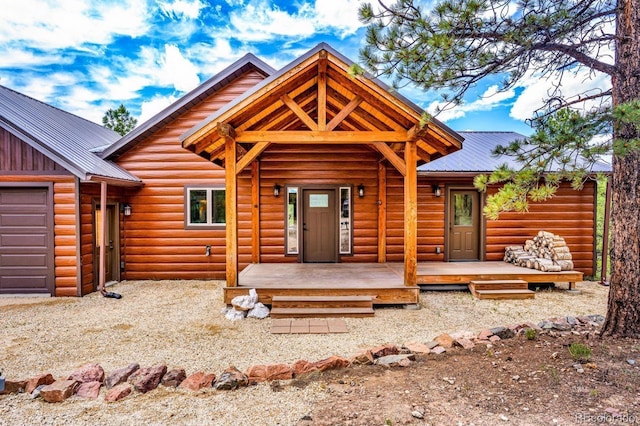 4513 County Road 323, Westcliffe, CO 81252 - view of front facade featuring a metal roof, log veneer siding, a garage, and covered porch
