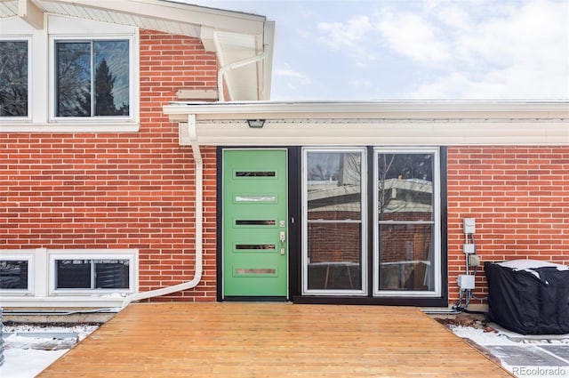 snow covered property entrance with a deck