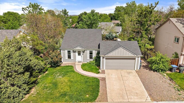 904 Clover Cir, Lafayette, CO 80026 - view of front of house featuring board and batten siding, driveway, a garage, a front lawn, and a shingled roof
