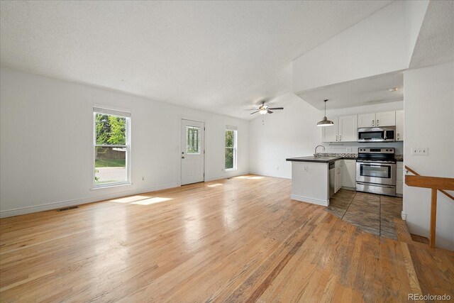 904 Clover Cir, Lafayette, CO 80026 - kitchen with appliances with stainless steel finishes, open floor plan, dark countertops, plenty of natural light, and lofted ceiling