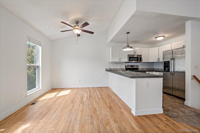 904 Clover Cir, Lafayette, CO 80026 - kitchen with appliances with stainless steel finishes, dark countertops, a sink, a peninsula, and a ceiling fan