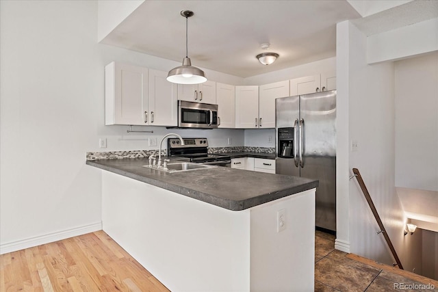 904 Clover Cir, Lafayette, CO 80026 - kitchen featuring appliances with stainless steel finishes, dark countertops, a peninsula, baseboards, and white cabinets