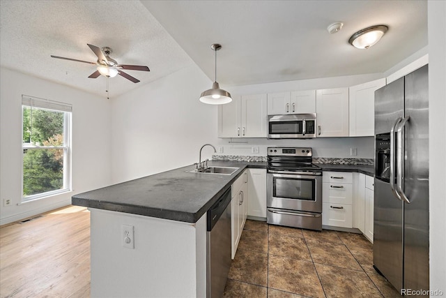 904 Clover Cir, Lafayette, CO 80026 - kitchen featuring stainless steel appliances, a sink, dark countertops, a peninsula, and a textured ceiling
