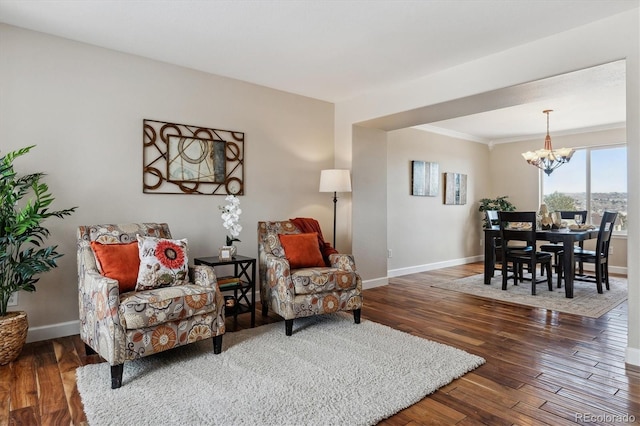 living room with dark wood-type flooring, crown molding, and a chandelier