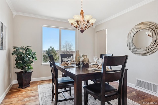 dining room featuring an inviting chandelier, a wealth of natural light, ornamental molding, and light hardwood / wood-style flooring