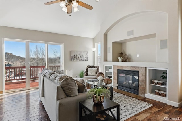 living room with lofted ceiling, ceiling fan, dark hardwood / wood-style floors, a mountain view, and a tiled fireplace