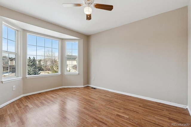 spare room with ceiling fan, plenty of natural light, and wood-type flooring