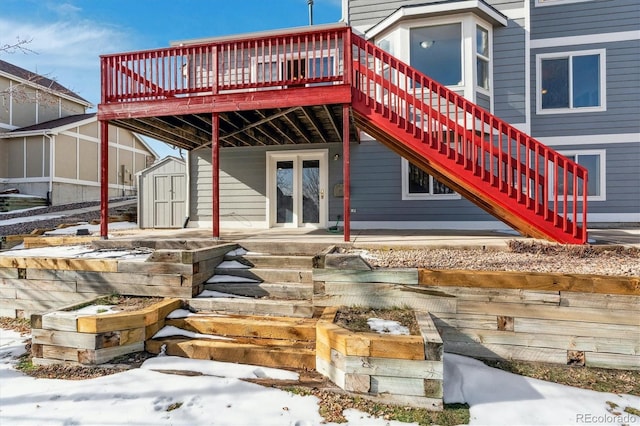 snow covered house featuring a wooden deck and a shed