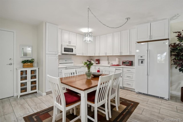 kitchen featuring white appliances, tasteful backsplash, sink, hanging light fixtures, and white cabinetry