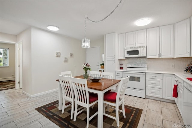 kitchen featuring white cabinets, tasteful backsplash, pendant lighting, baseboard heating, and white appliances