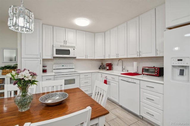 kitchen featuring white appliances, decorative backsplash, pendant lighting, and white cabinets