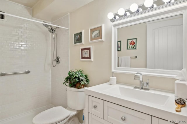 bathroom featuring vanity, a tile shower, and toilet