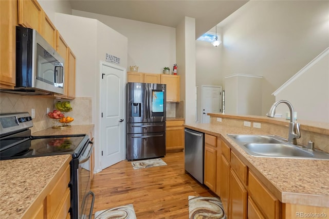 kitchen featuring light hardwood / wood-style floors, sink, backsplash, appliances with stainless steel finishes, and light brown cabinetry