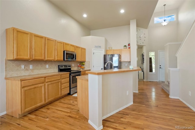 kitchen featuring high vaulted ceiling, backsplash, appliances with stainless steel finishes, and light hardwood / wood-style flooring