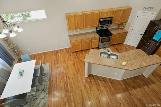 kitchen with a breakfast bar area, light hardwood / wood-style flooring, stainless steel appliances, and sink